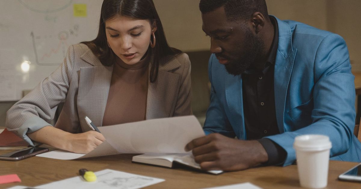 Two colleagues collaborating over documents at an office desk.
