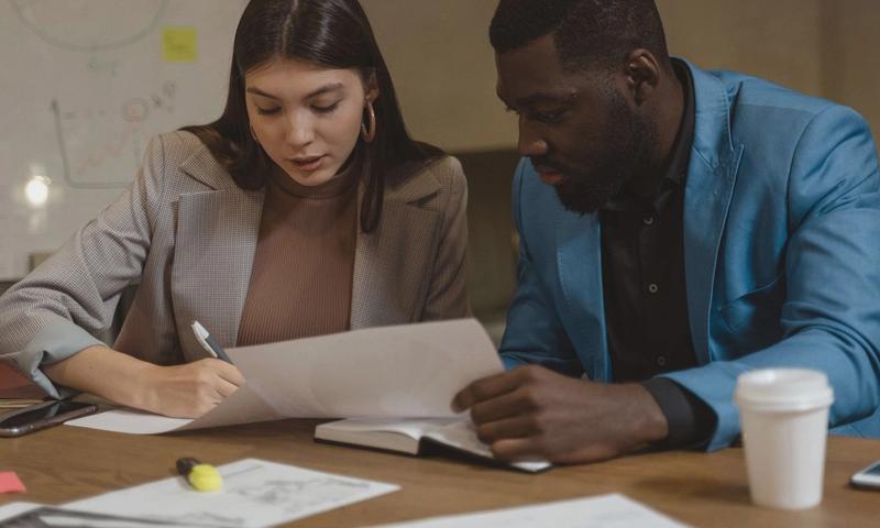 Two colleagues collaborating over documents at an office desk.