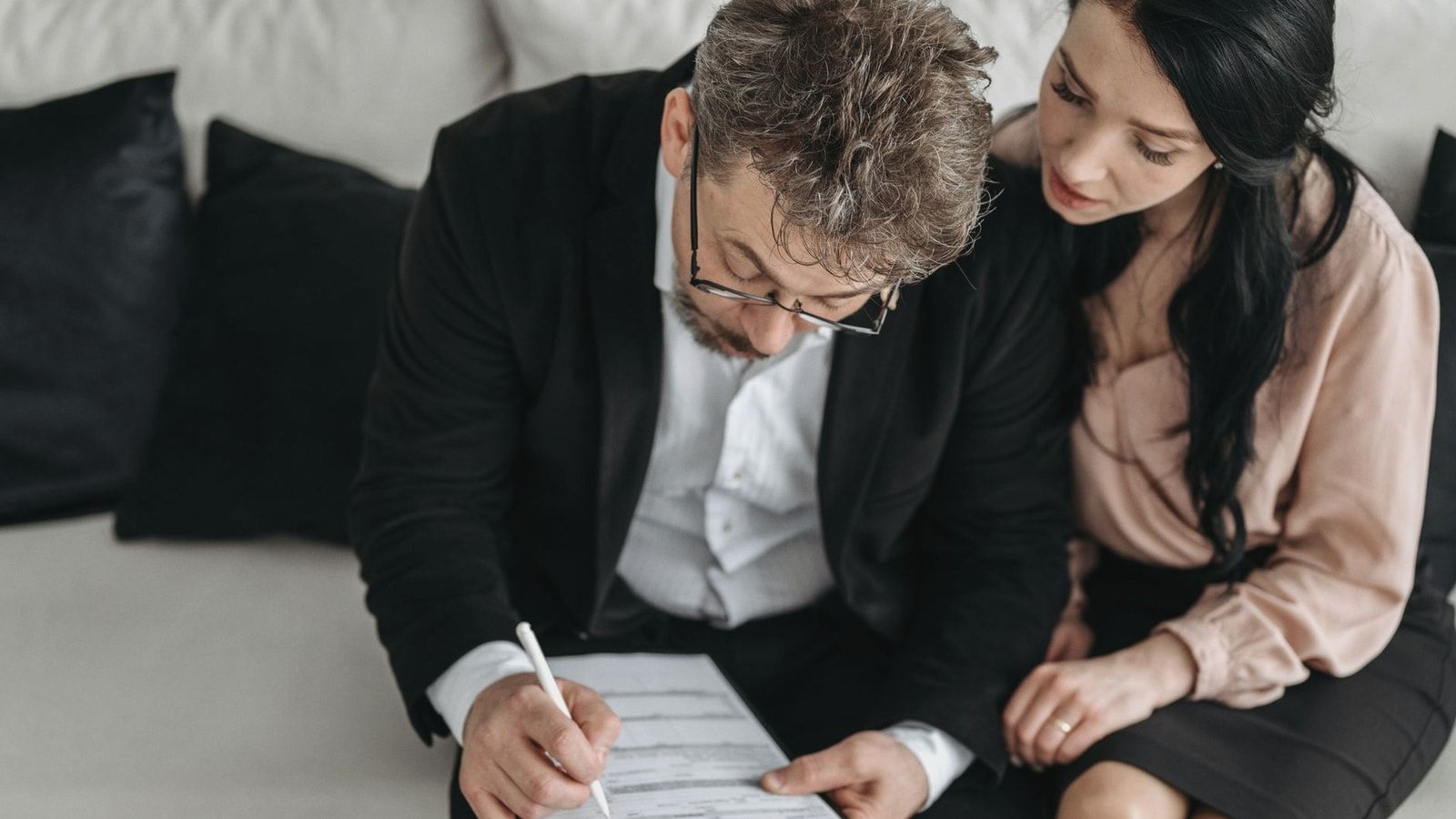 An adult couple sitting together reviewing documents in a modern indoor setting.