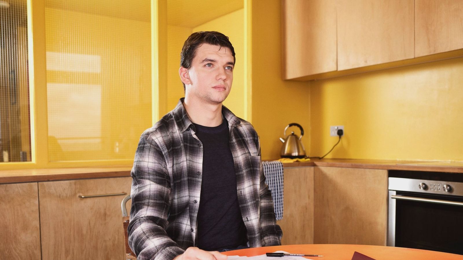Adult man sitting at kitchen table reviewing documents with focus and concentration.