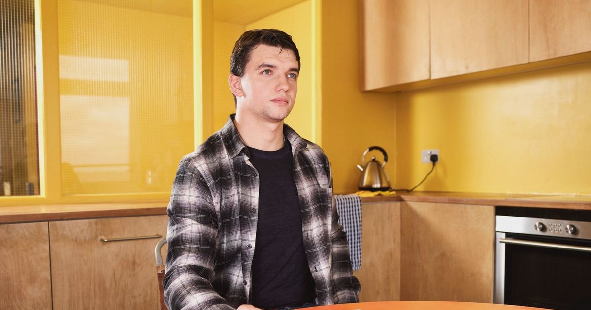 Adult man sitting at kitchen table reviewing documents with focus and concentration.