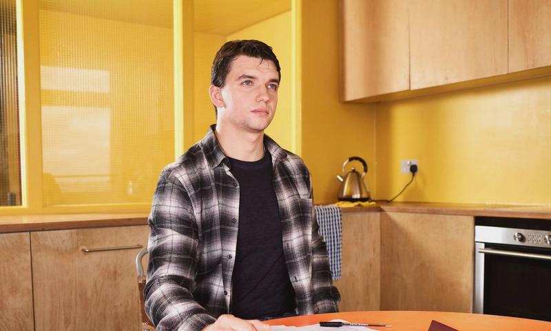Adult man sitting at kitchen table reviewing documents with focus and concentration.