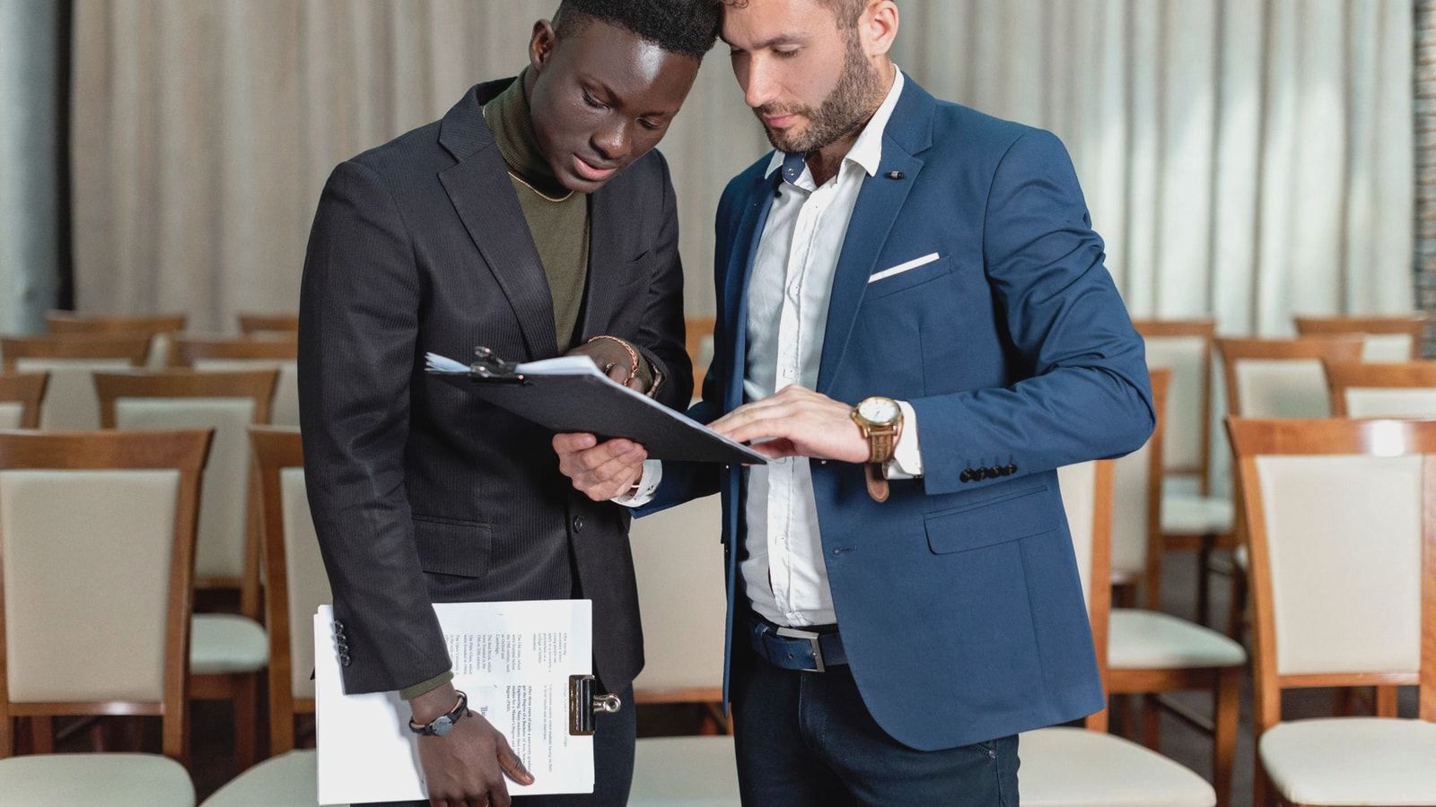 Two business professionals engaged in a detailed document review in a conference room.