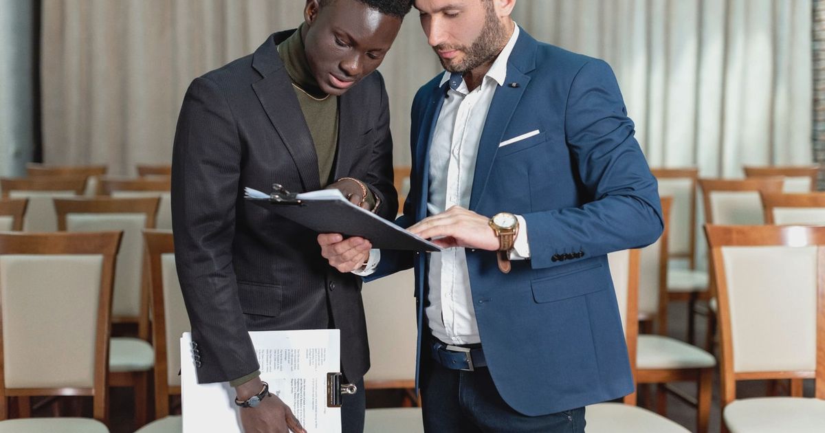 Two business professionals engaged in a detailed document review in a conference room.