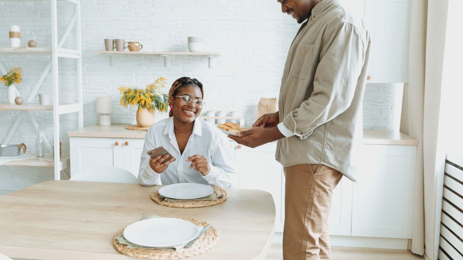 Young couple sharing a joyful morning breakfast in their cozy kitchen setting.
