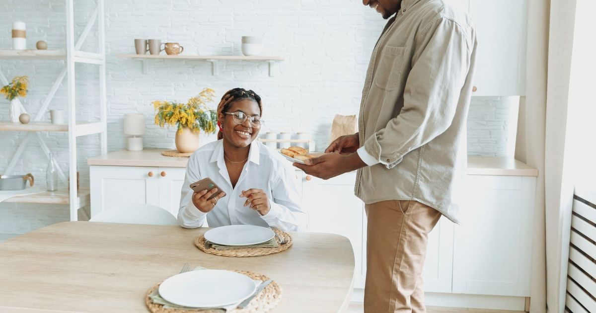 Young couple sharing a joyful morning breakfast in their cozy kitchen setting.
