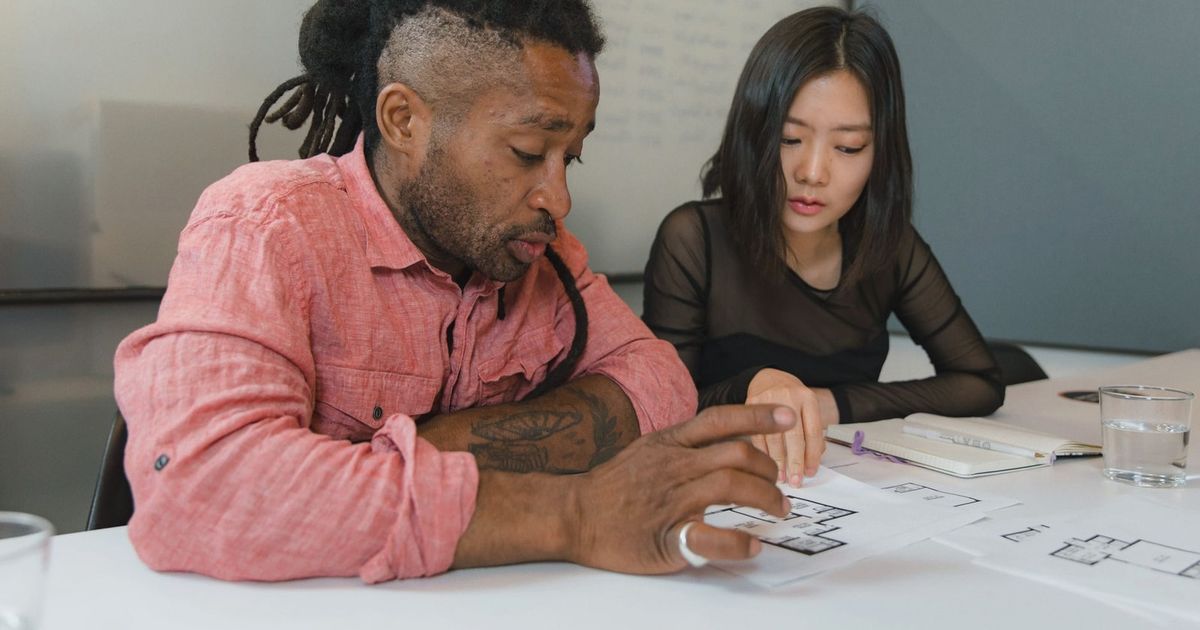 Two professionals engaged in planning during a business meeting, focusing on architectural designs.