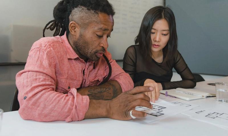 Two professionals engaged in planning during a business meeting, focusing on architectural designs.