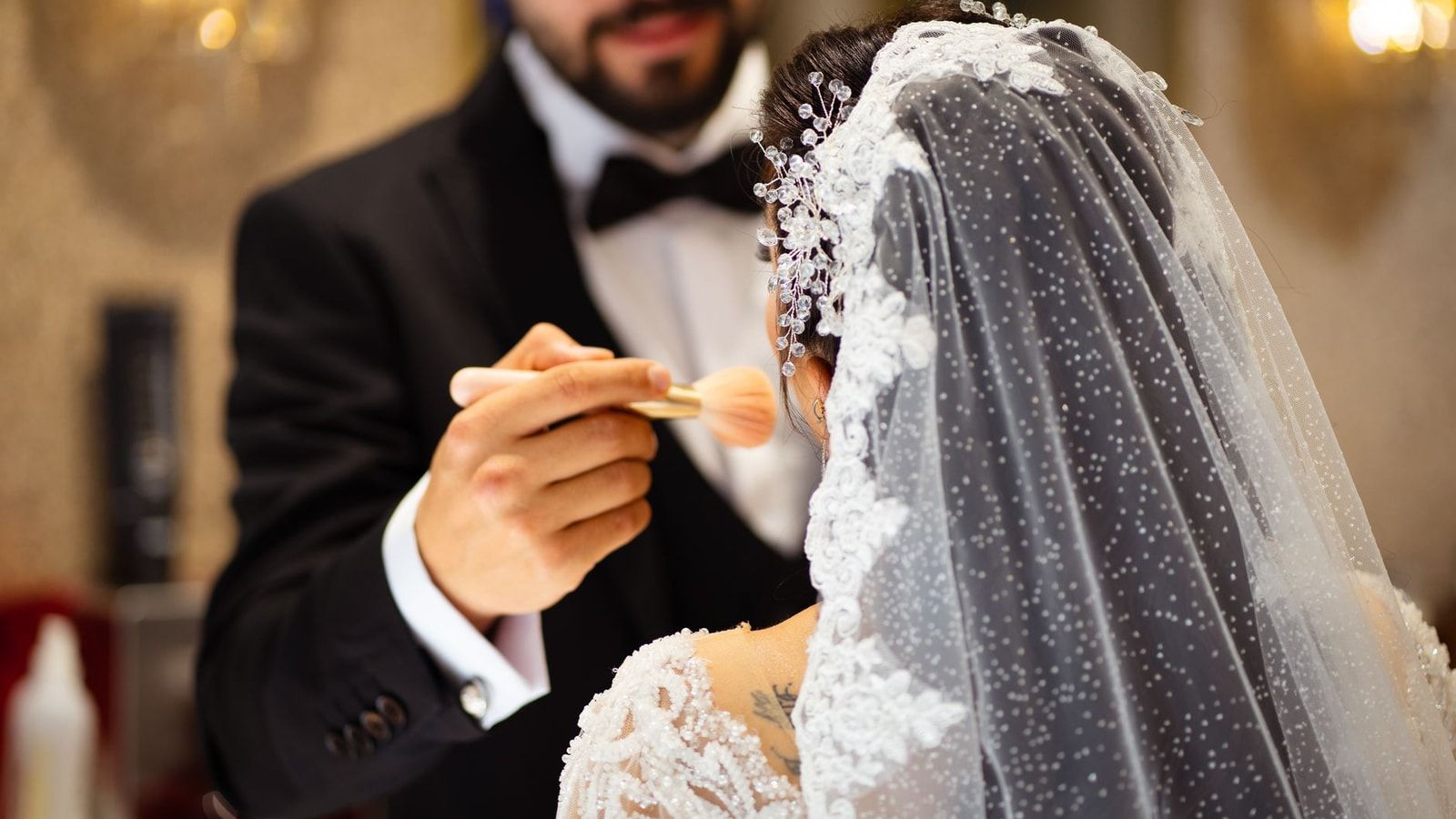 A bride receives makeup touch-up by groom before her wedding ceremony.