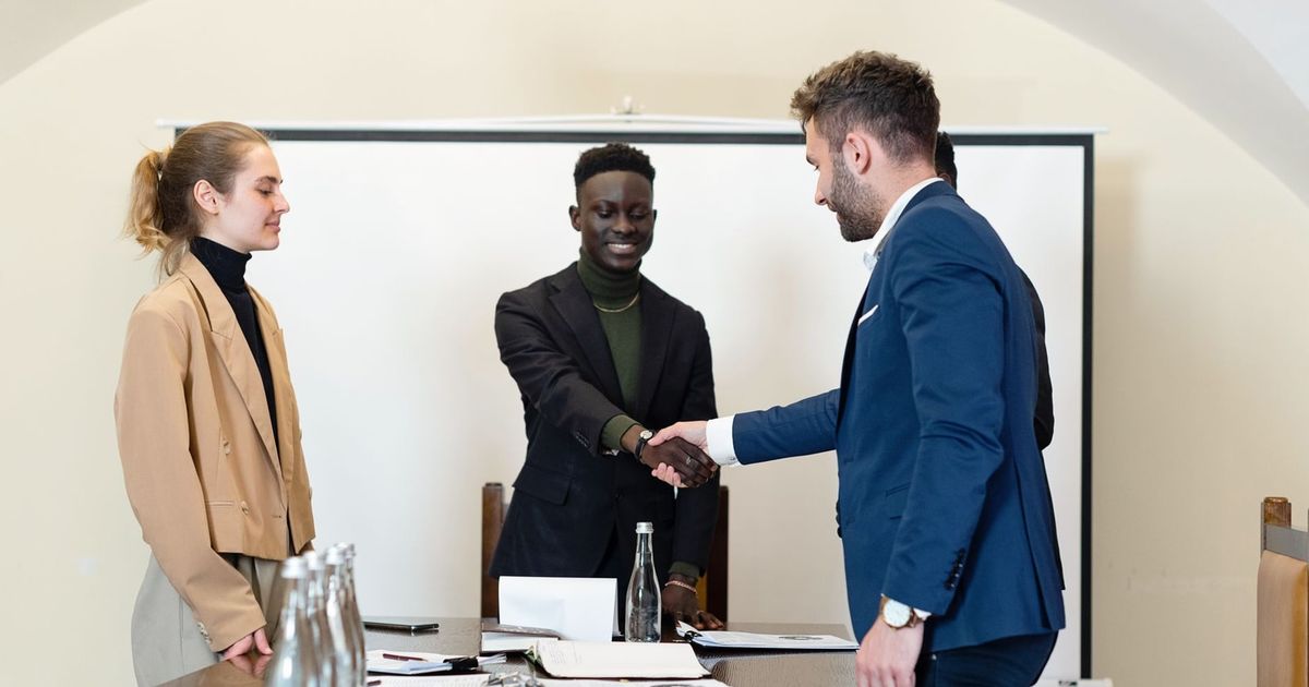 A diverse group of business professionals in a meeting room, shaking hands as a sign of agreement.