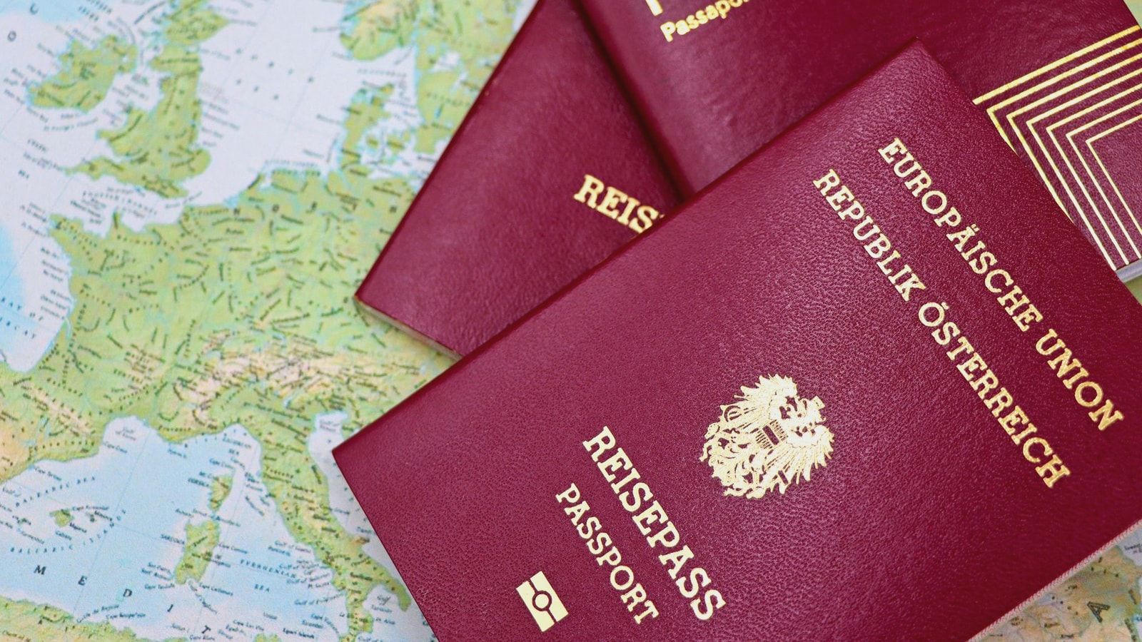 Close-up of European passports from Portugal and Austria on a world map.