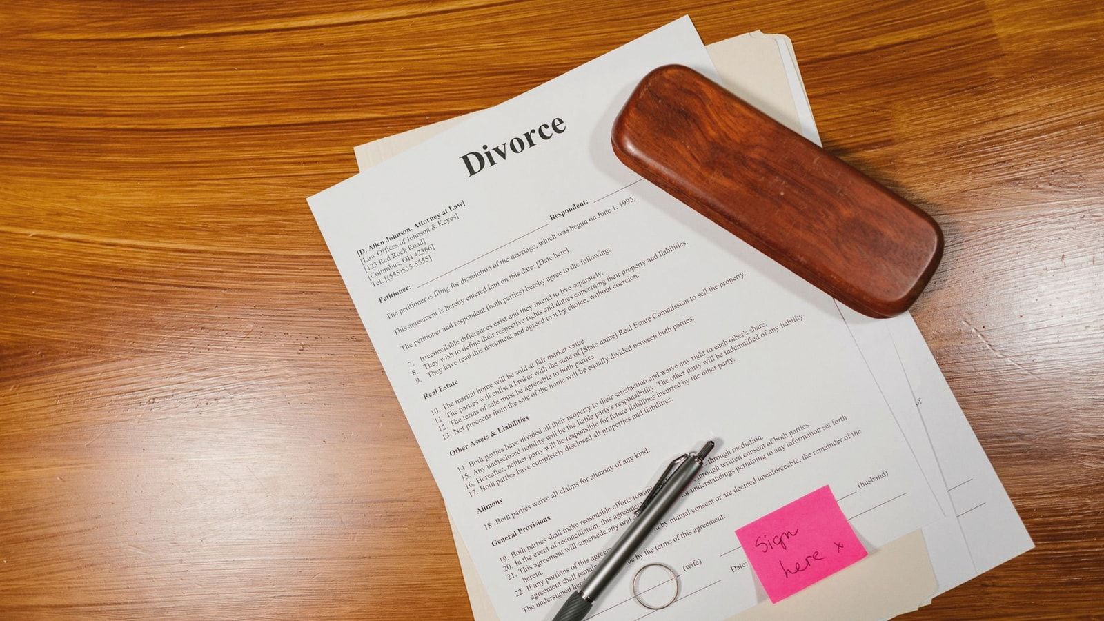 Flat lay of divorce papers with a pen and ring on a wooden table for legal themes.
