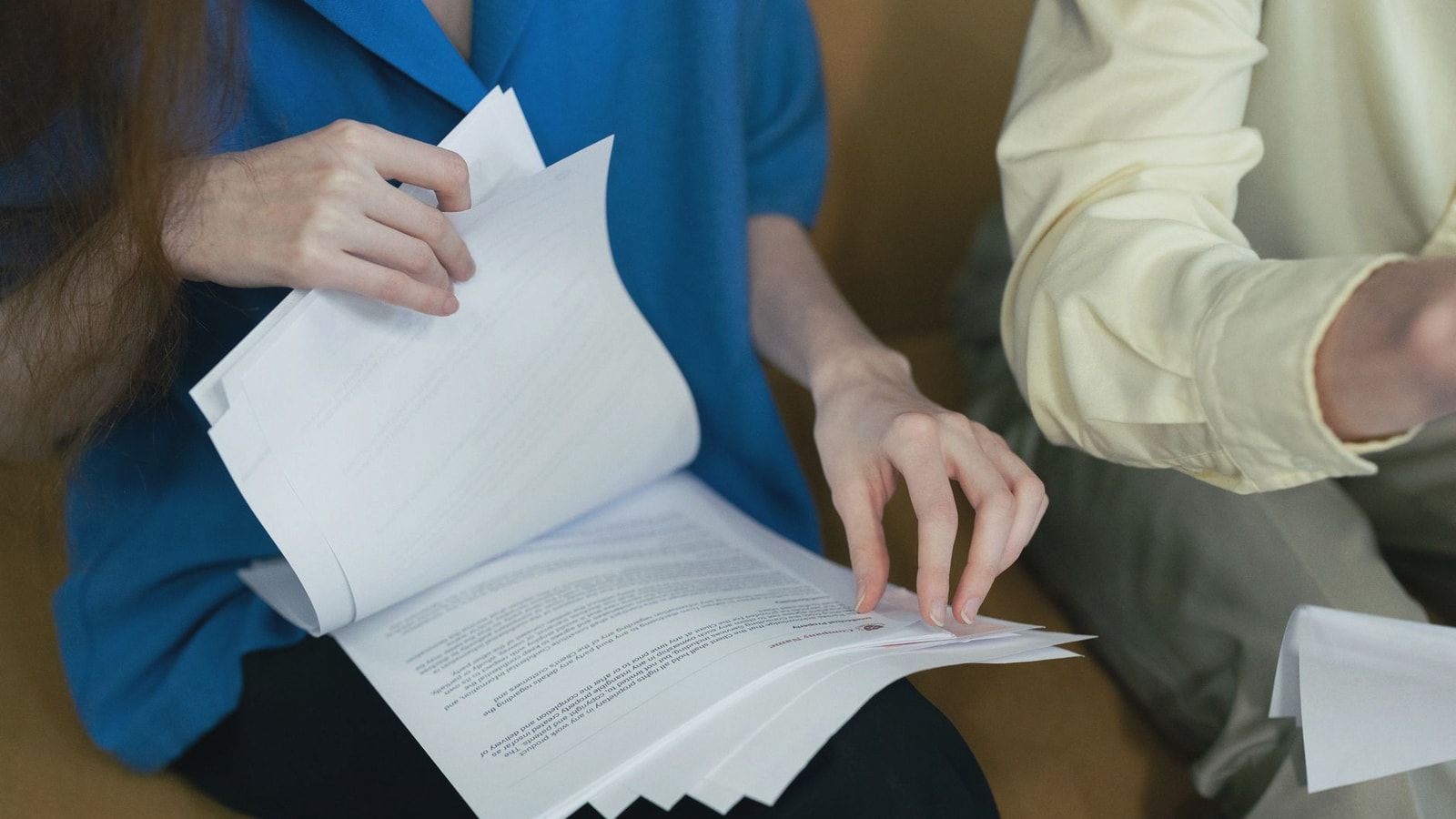 People in professional attire reviewing important documents together on a sofa.