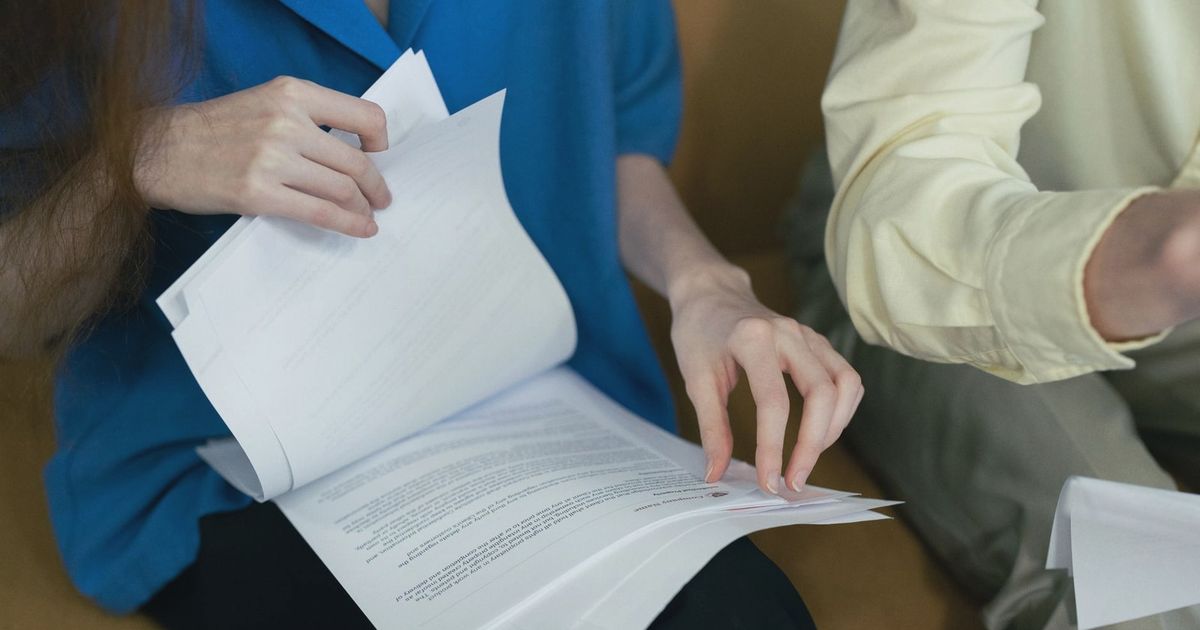 People in professional attire reviewing important documents together on a sofa.