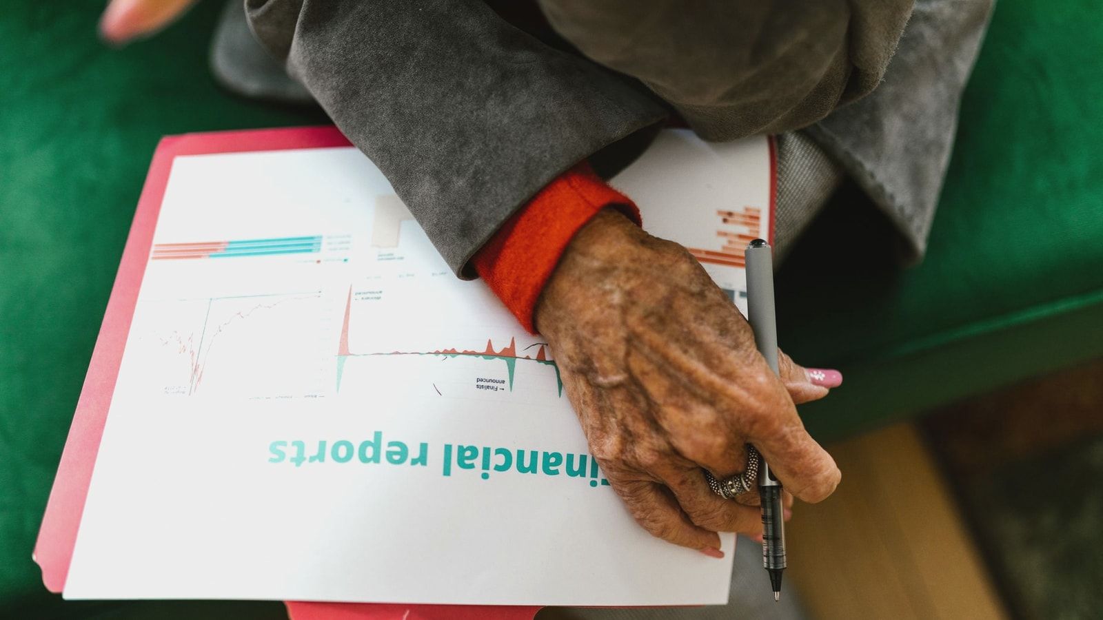 Close-up of an elderly woman holding a pen with a financial report.