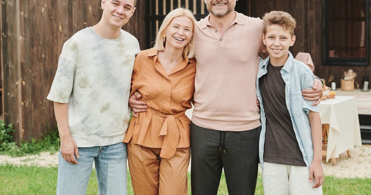 Smiling family of four posing outdoors, capturing love and togetherness.