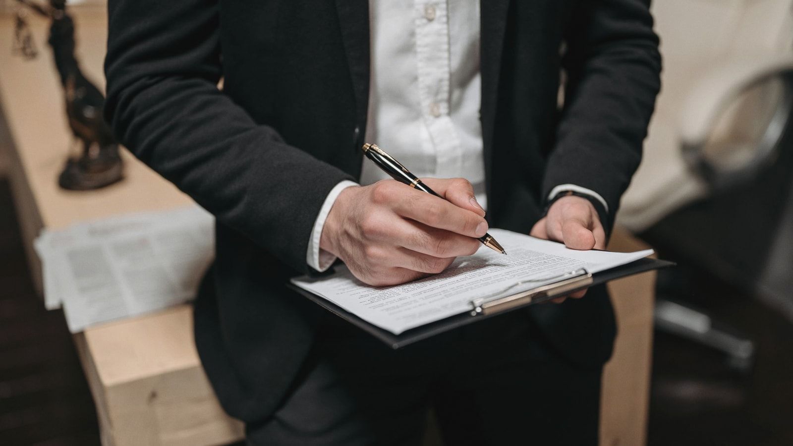 Business professional signing a contract on a clipboard at the office.