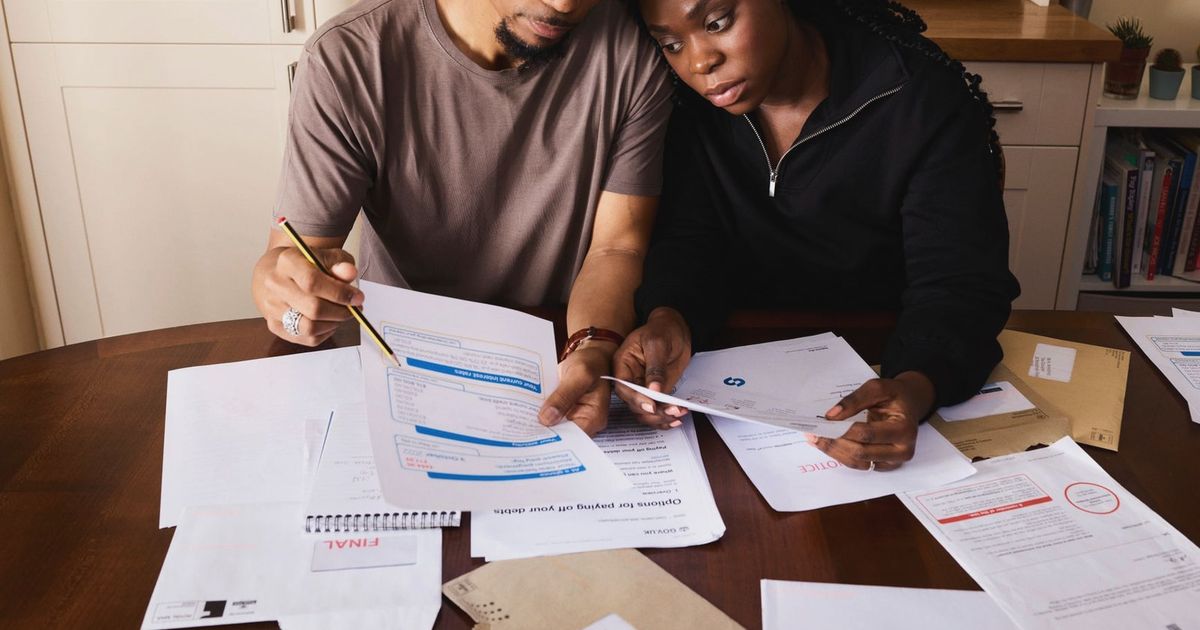 A couple sitting at a table reviewing financial documents, highlighting domestic budgeting.