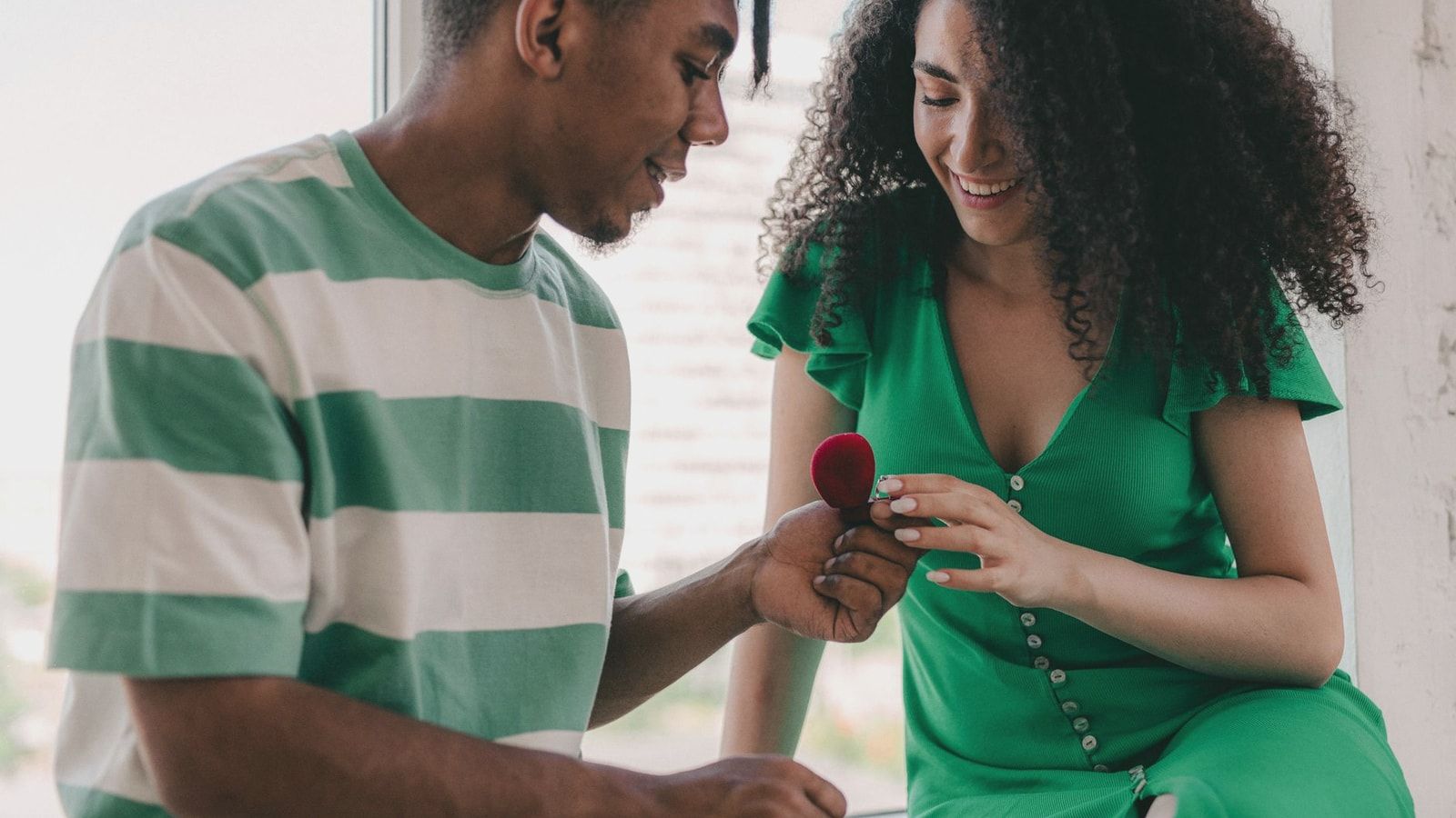 A young couple joyfully shares a moment as a marriage proposal unfolds indoors.