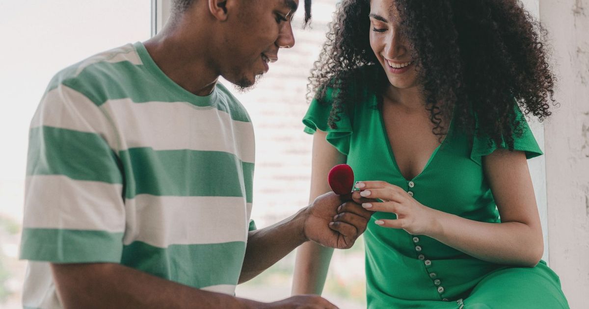 A young couple joyfully shares a moment as a marriage proposal unfolds indoors.