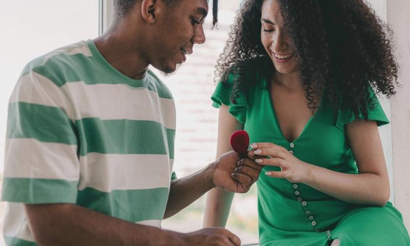 A young couple joyfully shares a moment as a marriage proposal unfolds indoors.