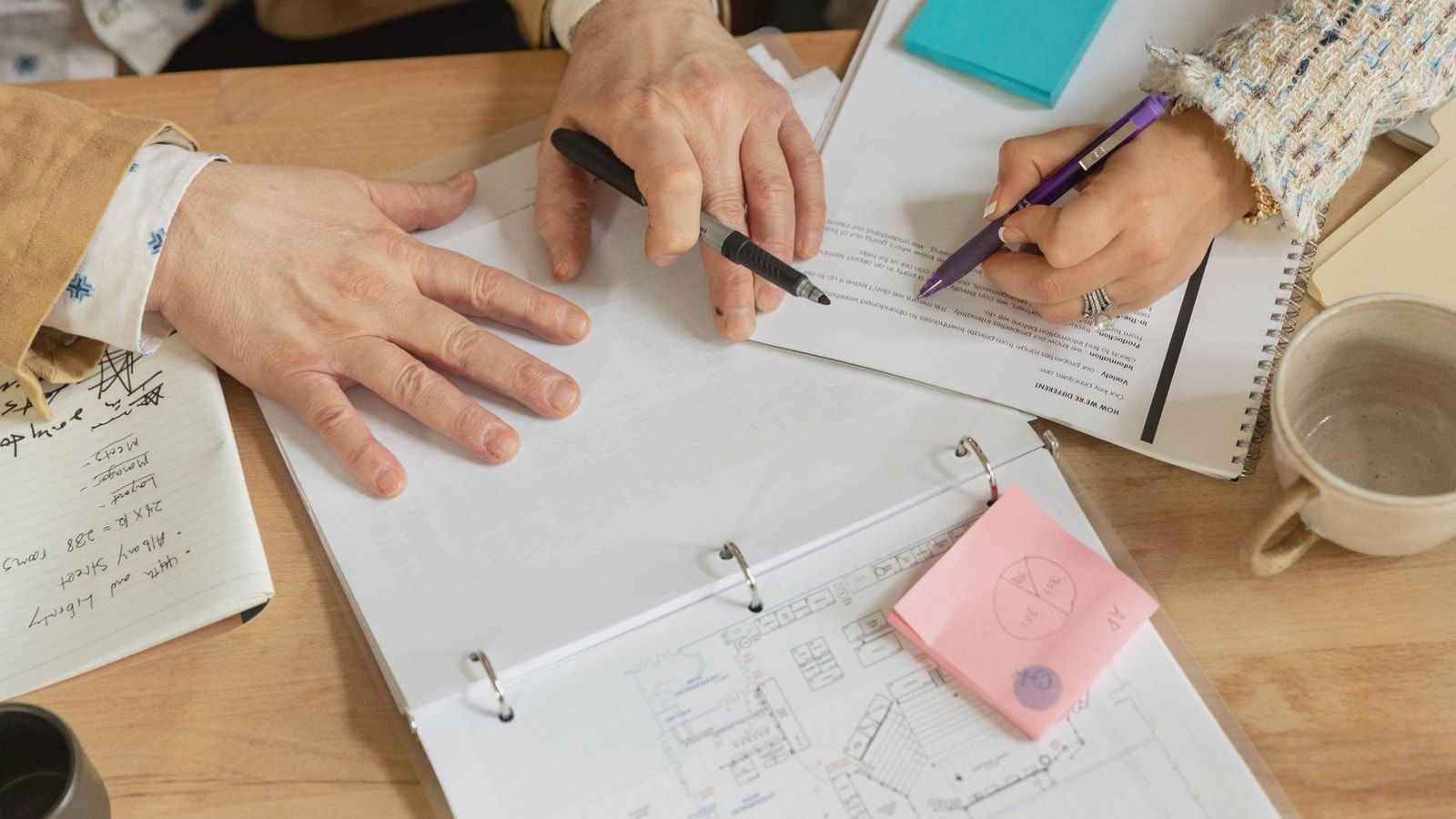 Close-up of two coworkers collaborating over documents and planning in an office setting.