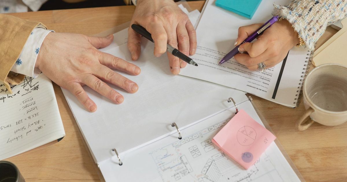 Close-up of two coworkers collaborating over documents and planning in an office setting.