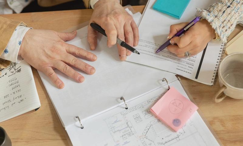 Close-up of two coworkers collaborating over documents and planning in an office setting.