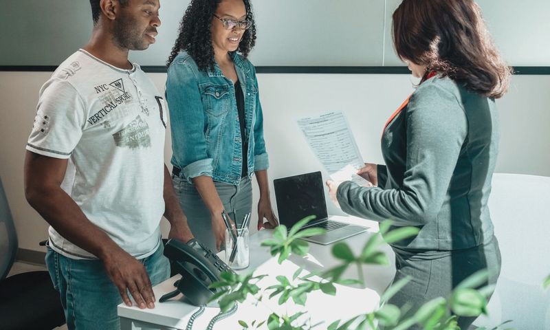 A diverse group in a business meeting discussing documents in a modern office setting.