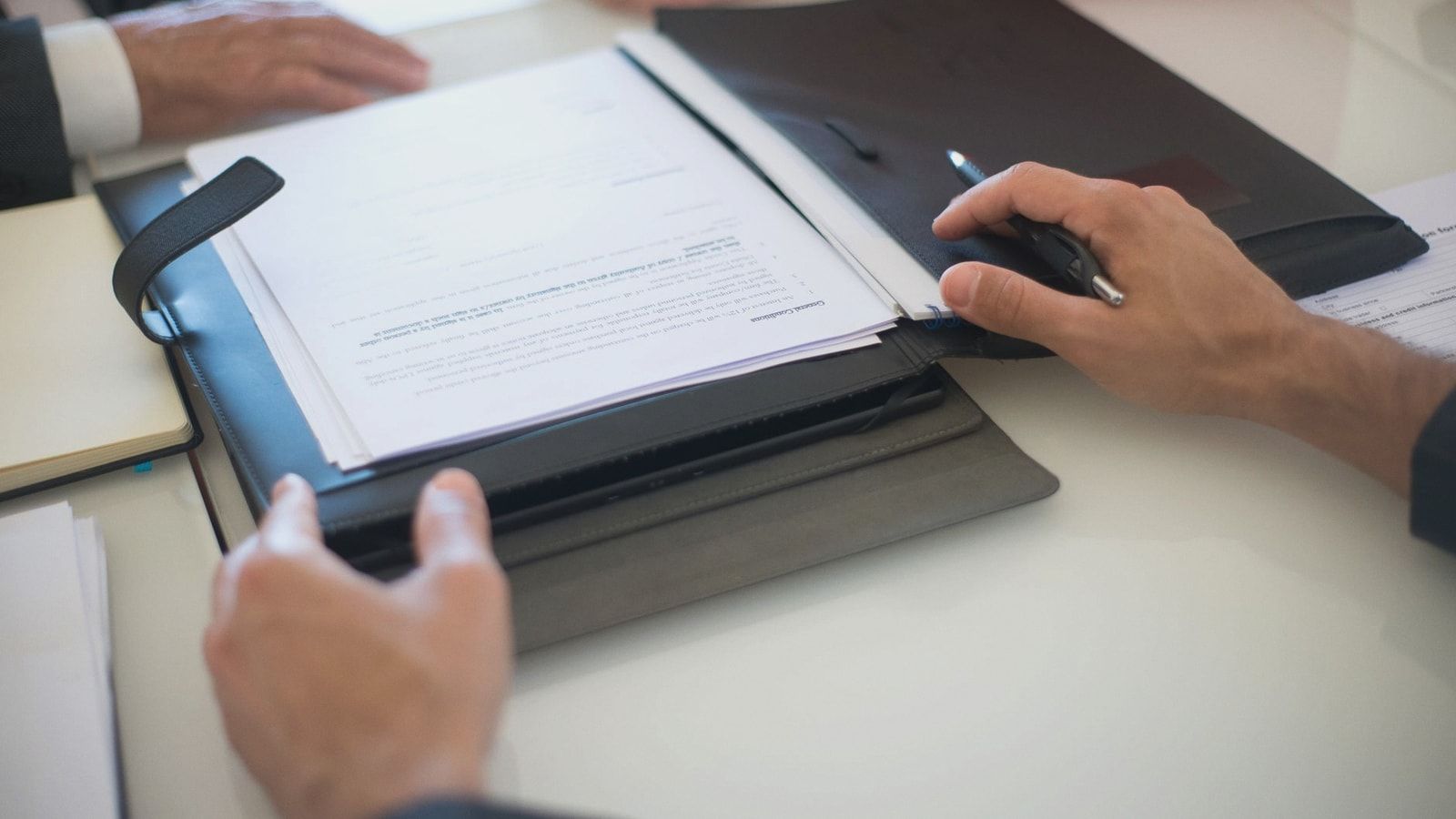 Two professionals discussing a contract with documents on a table, indoors.