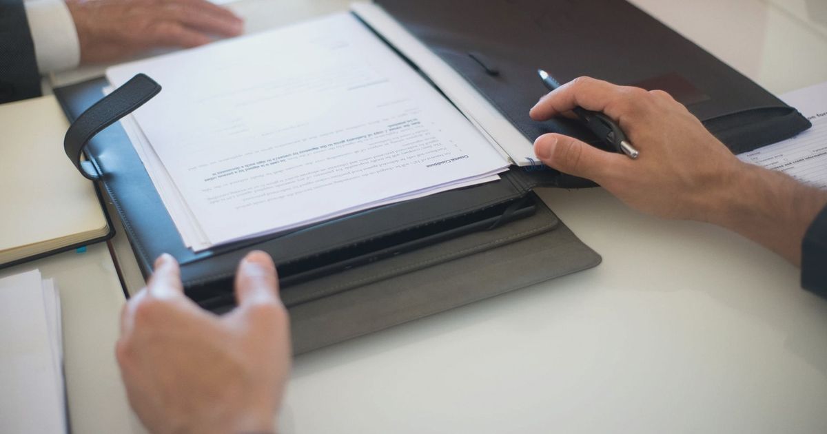 Two professionals discussing a contract with documents on a table, indoors.