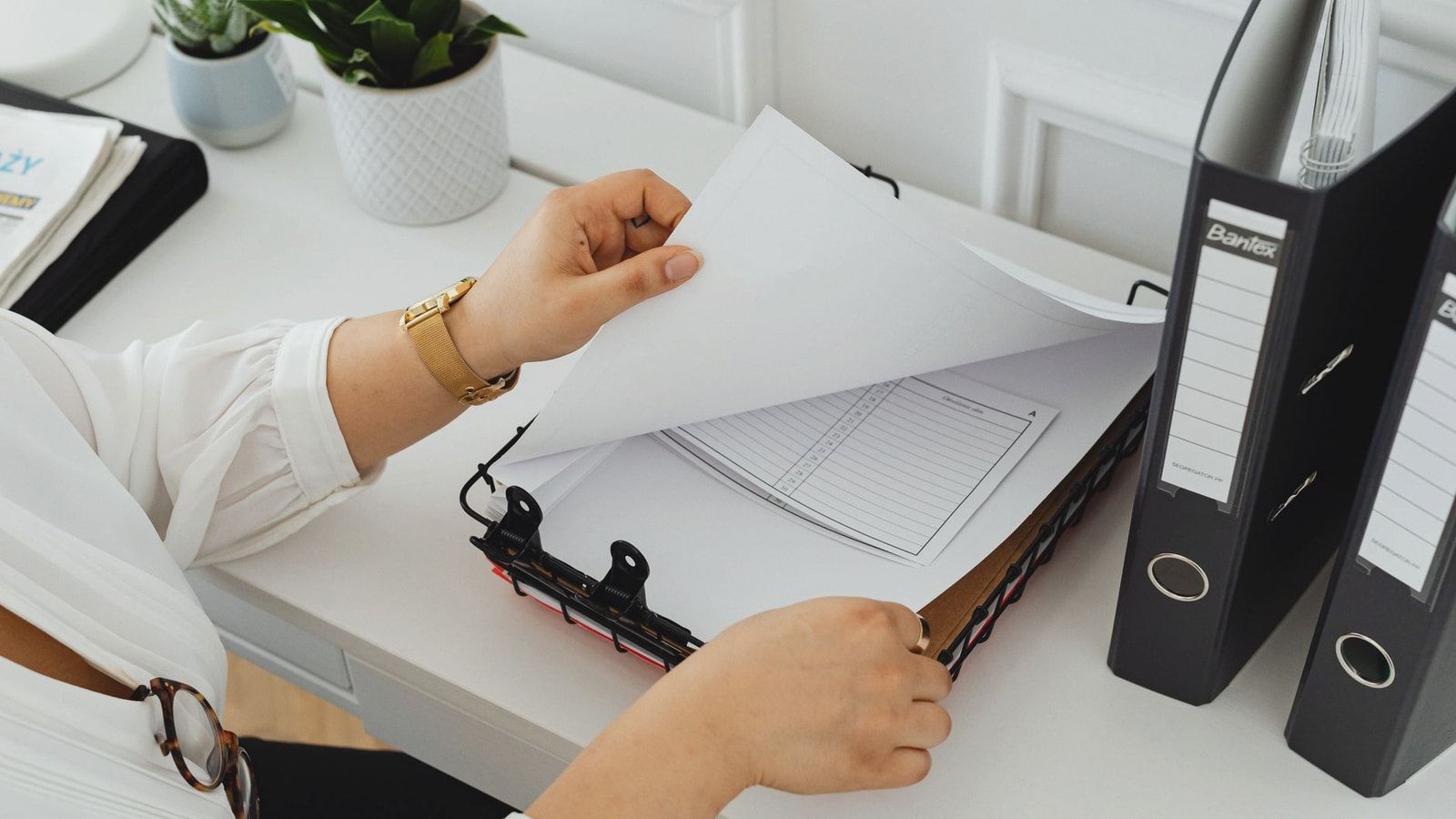 Business professional sorting through documents in a modern office setting.