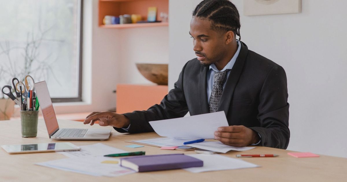 Focused businessman working with laptop and documents in a modern office setting.