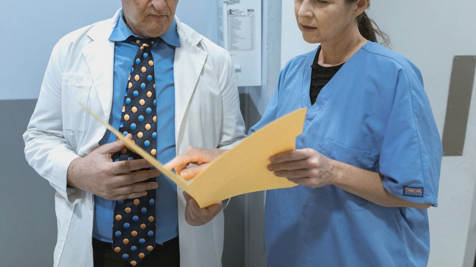 Doctor and nurse examining patient records in a clinical setting.