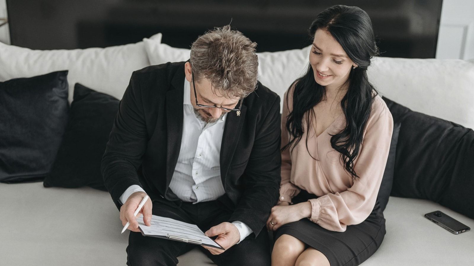 Business couple reviewing documents together on a couch, highlighting teamwork and success indoors.