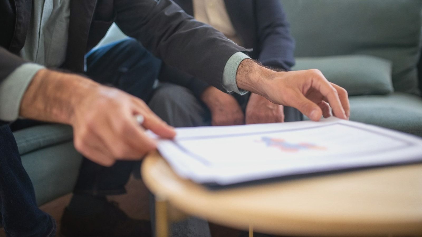 Two men discussing documents during a business meeting, focusing on paperwork.
