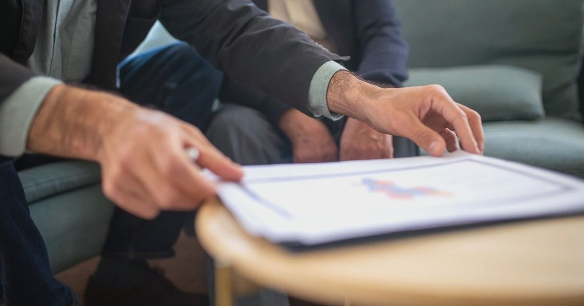 Two men discussing documents during a business meeting, focusing on paperwork.