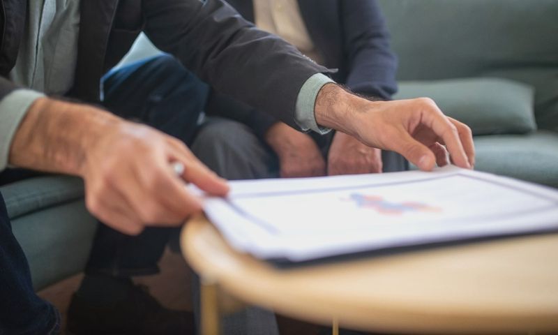 Two men discussing documents during a business meeting, focusing on paperwork.