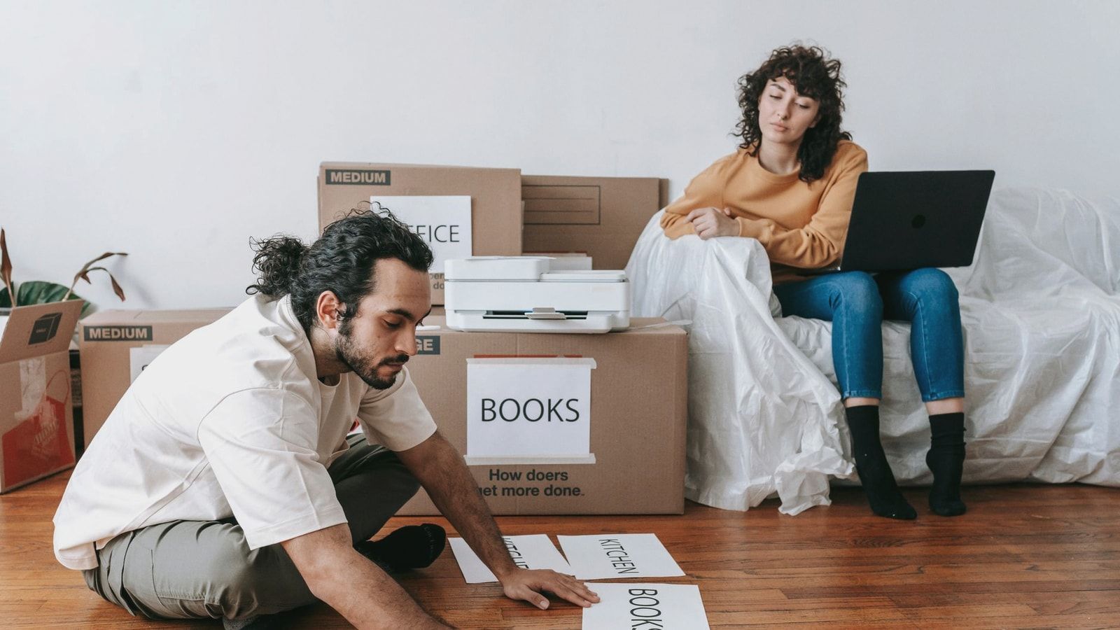 Couple organizing labels for packing and moving in a modern home setting.