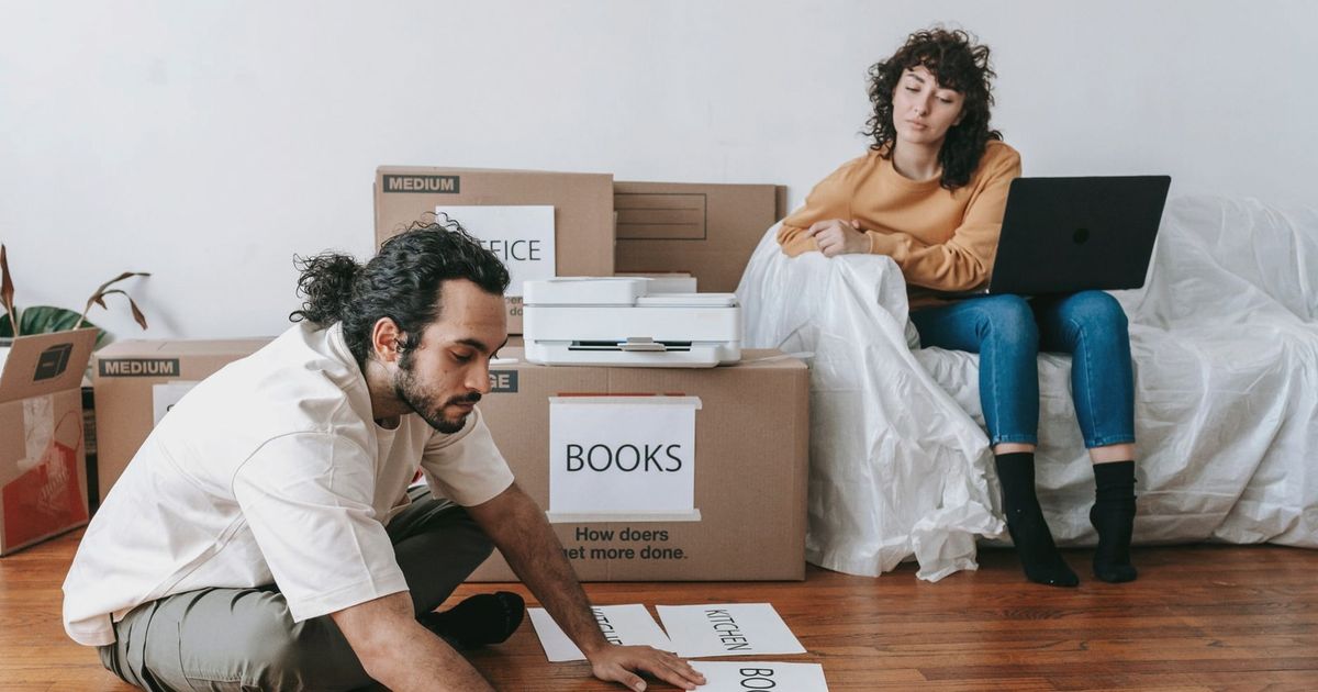 Couple organizing labels for packing and moving in a modern home setting.