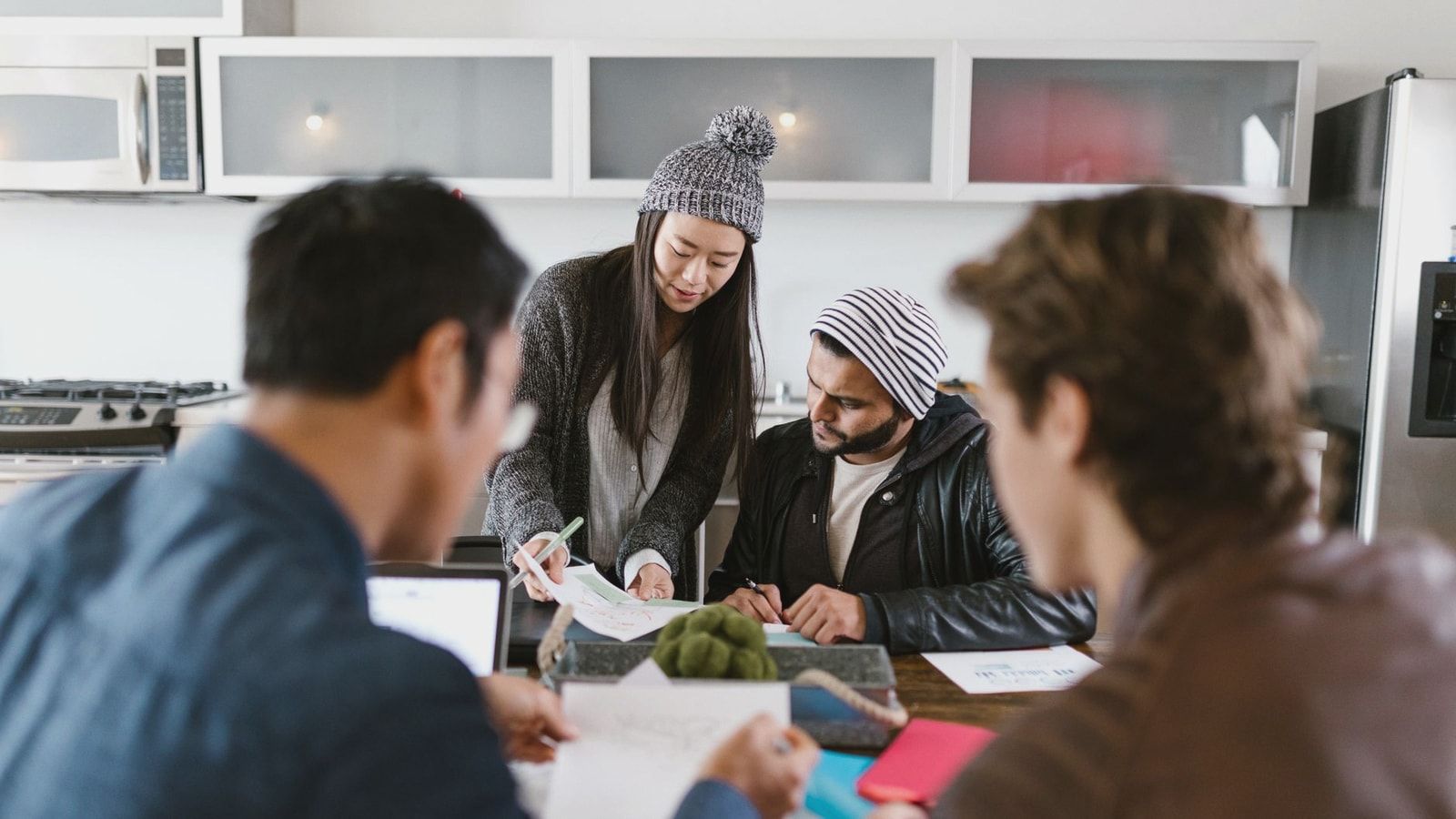 A dynamic group of young entrepreneurs brainstorming in a well-lit office space.