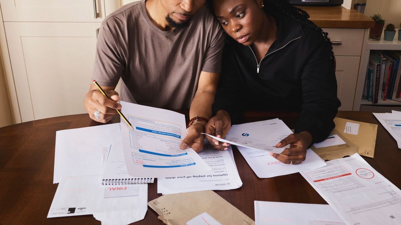 A couple sitting at a table reviewing financial documents, highlighting domestic budgeting.