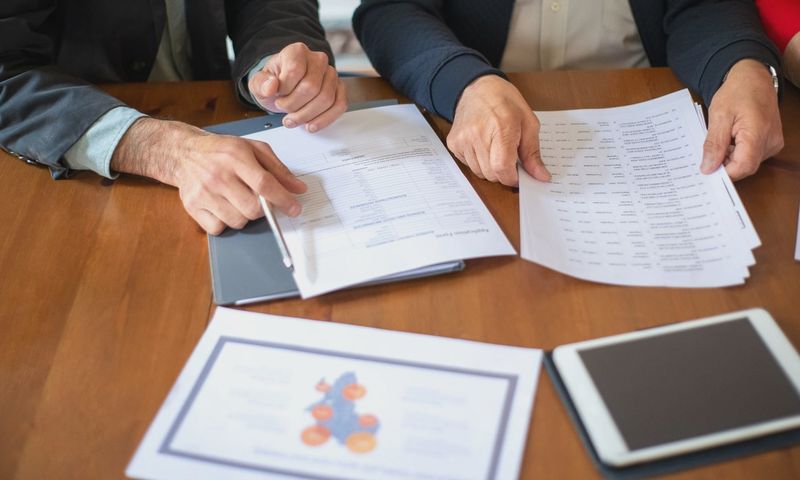 Two business professionals discussing and reviewing documents during a meeting.