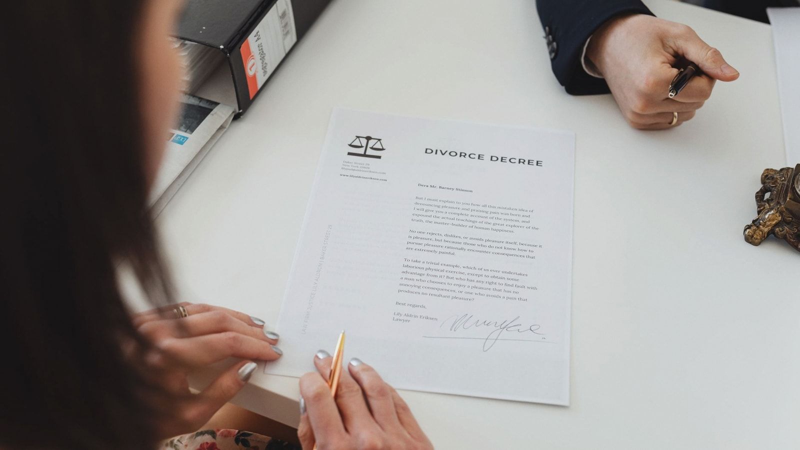 A close-up shot of two people signing a divorce decree at a law office table.