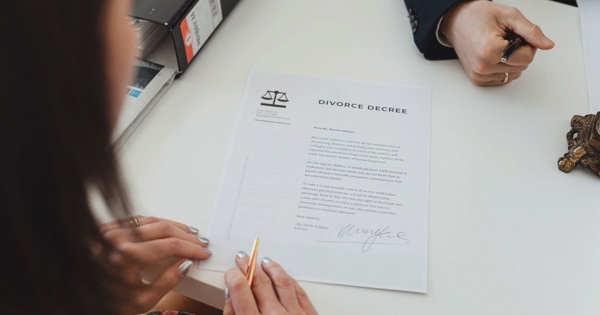 A close-up shot of two people signing a divorce decree at a law office table.