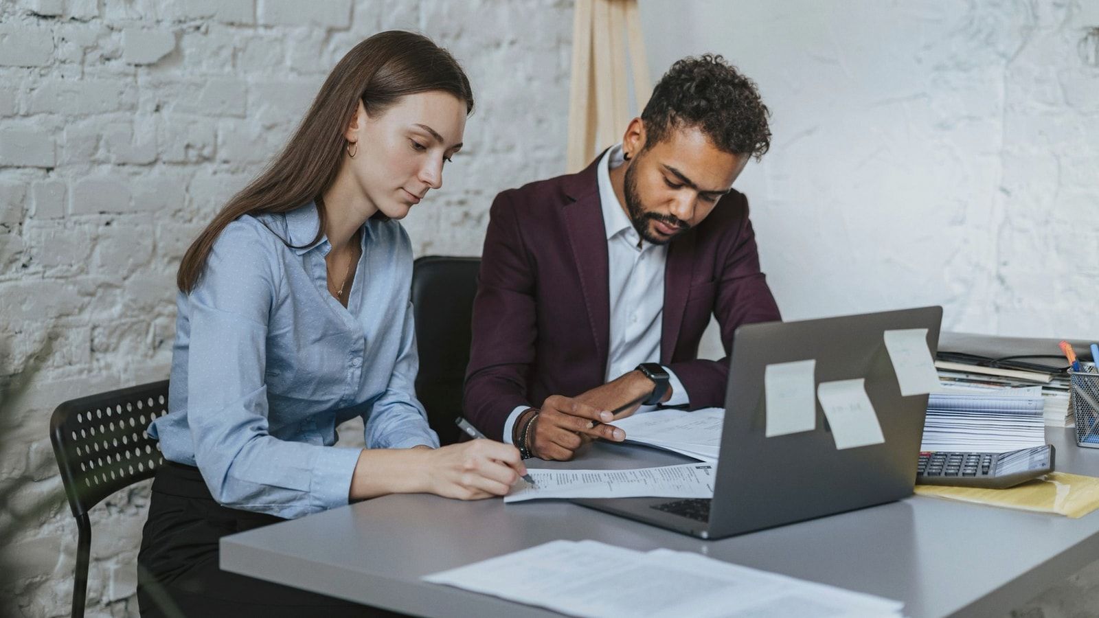 Two professionals working together at a desk in a modern office environment.