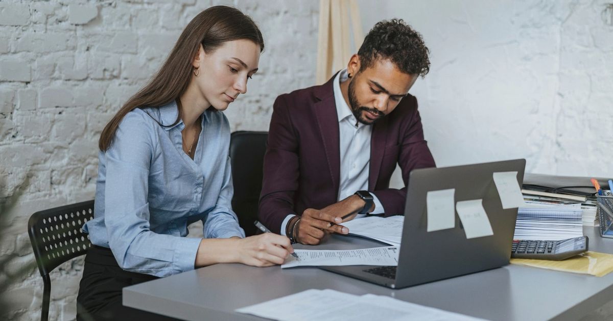 Two professionals working together at a desk in a modern office environment.