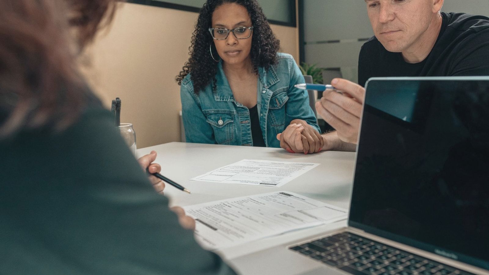 A couple reviewing documents with a professional in an office setting, focusing on financial planning.