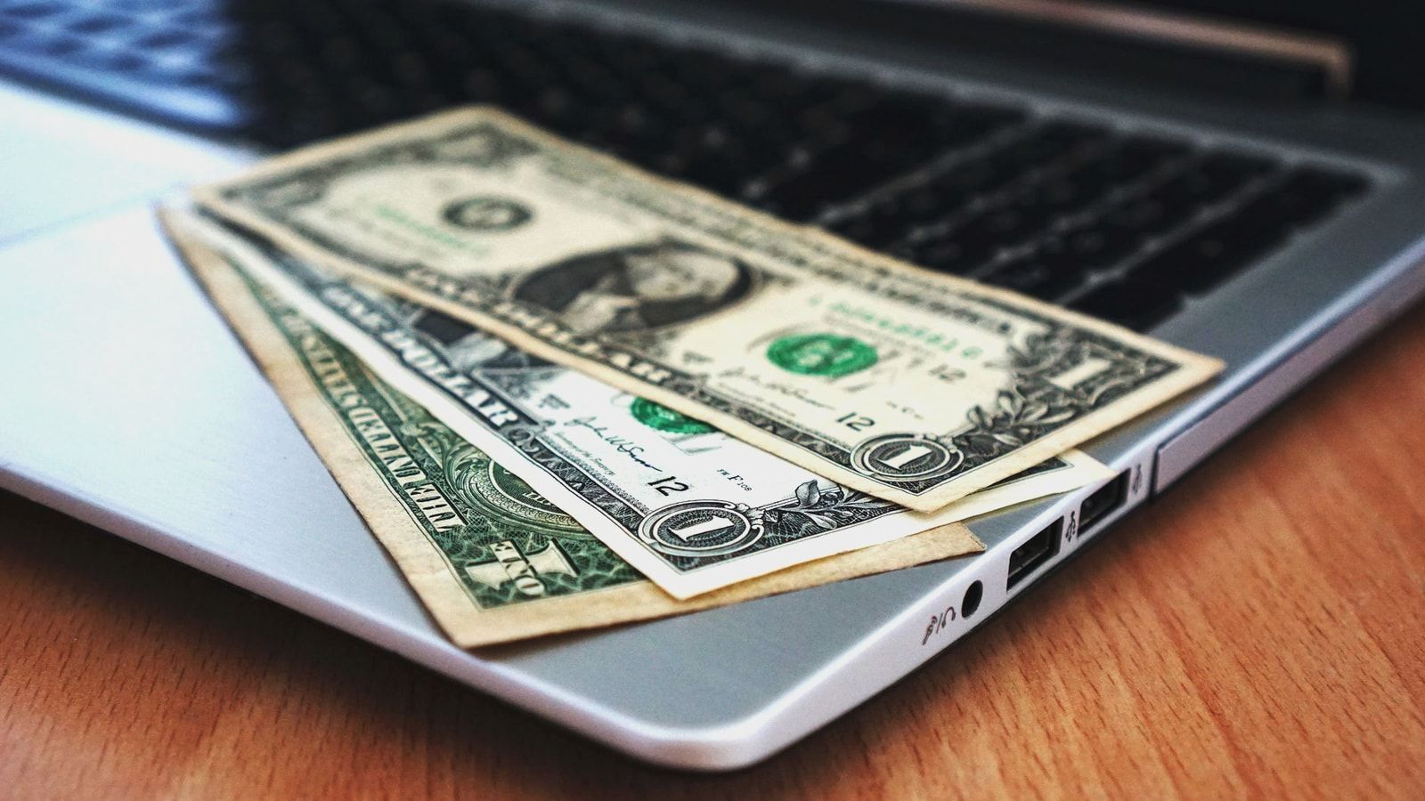 Close-up of US dollar bills placed on a laptop symbolizing digital finance and economy.