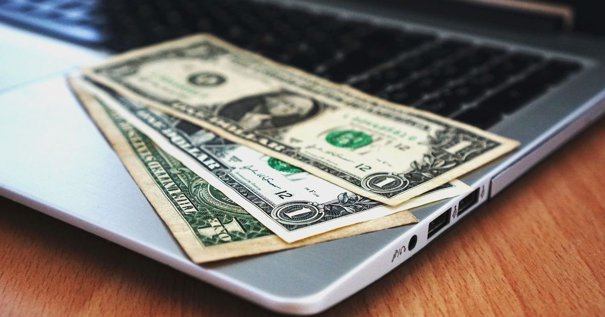 Close-up of US dollar bills placed on a laptop symbolizing digital finance and economy.